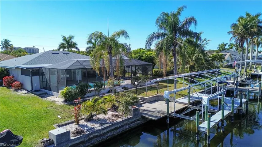 Dock area featuring a yard, boat lift, a lanai, a sunroom, and a water view