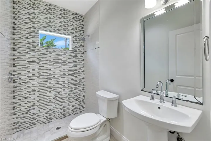 Pedestal sink with chrome fixtures and an ornate framed mirror