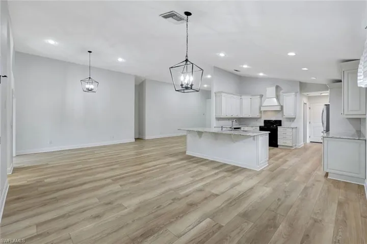 Open-concept living space featuring wood-finish flooring, recessed lighting, and two geometric pendant lights