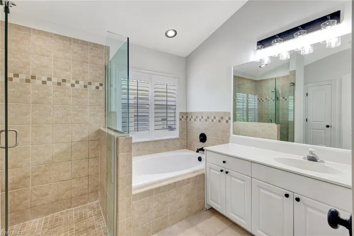 Spacious bathroom with a walk-in shower, built-in soaking tub, dual-sink vanity, and white plantation shutters