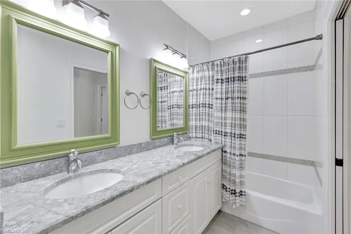 Dual vanity with an undermount sink, a stone countertop, and decorative framed mirrors