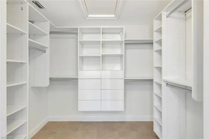 Custom closet system featuring extensive shelving, multiple hanging rods, integrated drawers, and a skylight