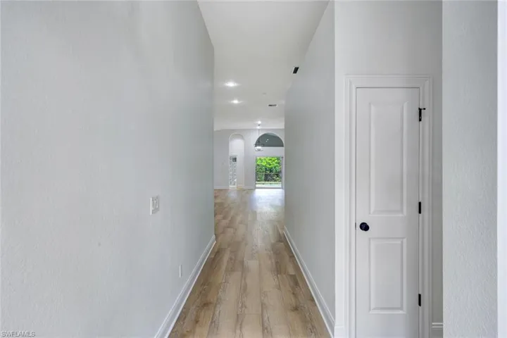 Hallway with wood-finish flooring and recessed lighting