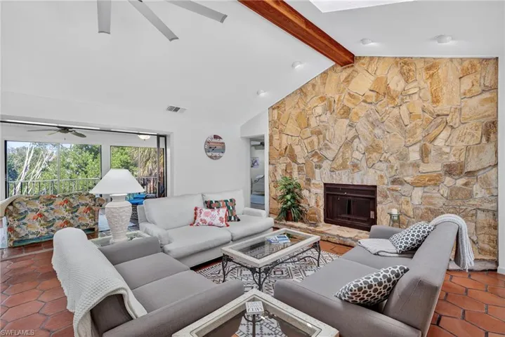 Light-filled living room with soaring ceilings, wood-burning fireplace, lanai surrounded by nature.