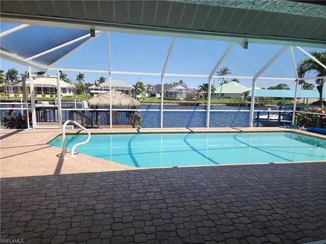 Pool with a water view, a boat dock, a patio, a residential view, and a lanai