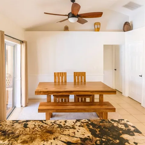 Dining room featuring vaulted ceiling, light tile patterned floors, and ceiling fan