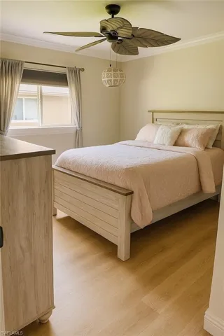 Guest bedroom 1 with ornamental molding, light wood-style floors, and ceiling fan