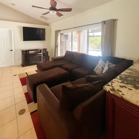 Tiled living room with vaulted ceiling and ceiling fan