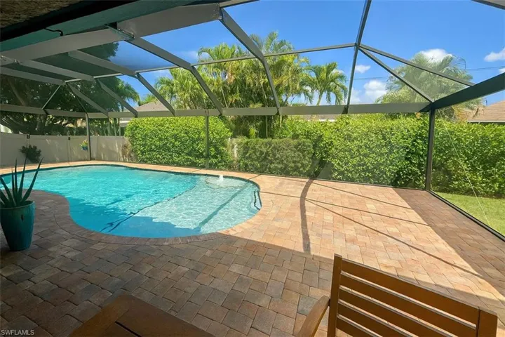 View of pool with a screened enclosure, and a patio area