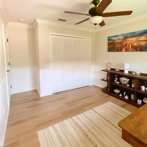 Guest bedroom 2 with wood finished floors, a ceiling fan, and ornamental molding