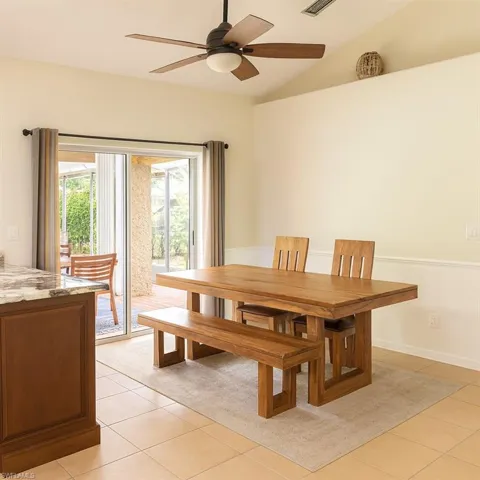 Dining space with vaulted ceiling, light tile patterned flooring, and a ceiling fan
