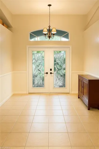 Entryway with french doors, tile patterned floors, and a chandelier