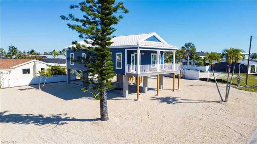 Beach home with a metal roof, a deck, a carport, and driveway - -VIRTUALLY EDITED