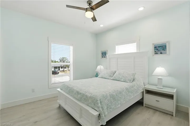Primary Bedroom featuring Luxury vinyl flooring, two windows with blinds, recessed lighting, and a ceiling fan - Virtually Edited Image