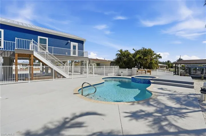 Outdoor oasis featuring a freeform pool, integrated spa, and spacious concrete patio - Virtually Edited Image