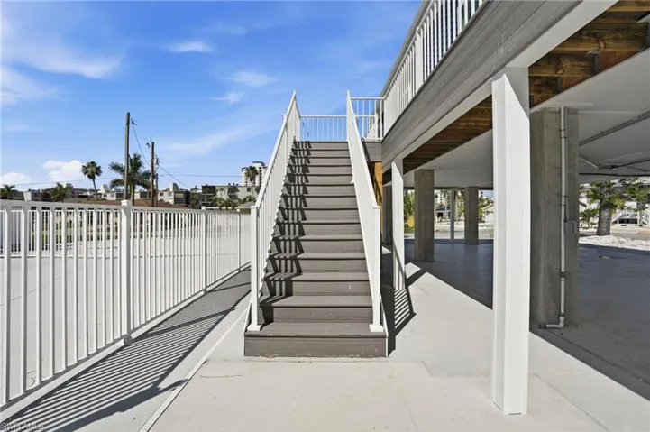 Exterior elevated entry featuring composite decking stairs and white railings - Virtually Edited Image