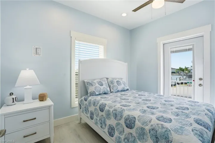 Light blue wall paint and white trim, featuring a ceiling fan, recessed lighting, and wood-finish flooring - Virtually Edited Image