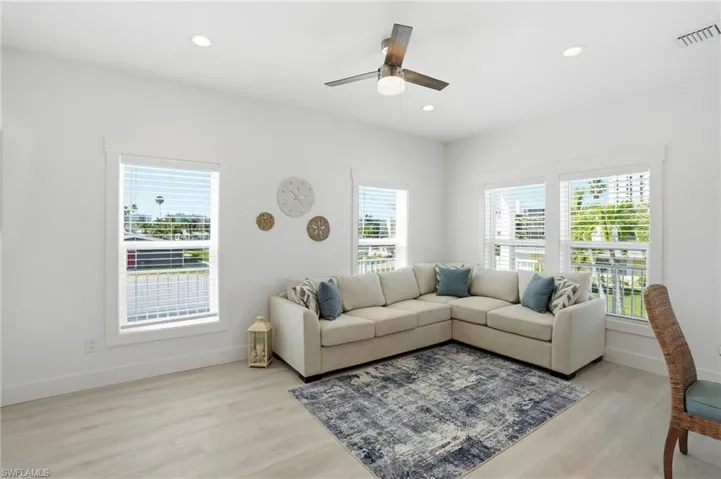 Bright interior space featuring light wood-finish flooring, recessed lighting, and a ceiling fan with light fixture - Virtually Edited Image
