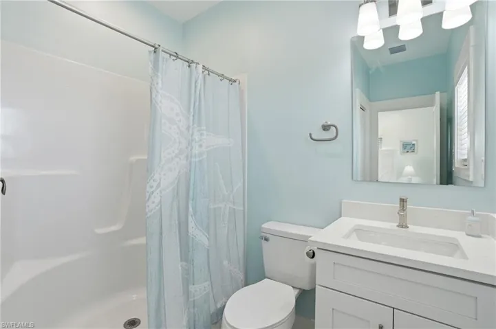 Full bathroom featuring a white vanity with an integrated sink, a sleek mirror, and a shower-tub combination with a white surround - Virtually Edited Image