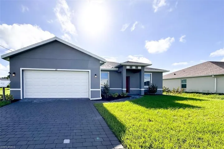 View of front of property featuring a garage and a front lawn