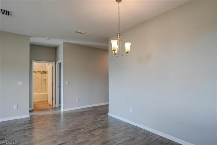 Unfurnished room featuring hardwood / wood-style flooring and an inviting chandelier