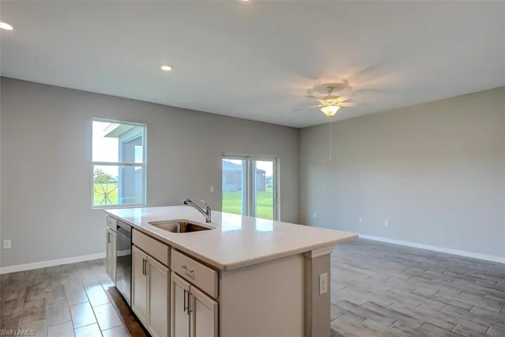 Kitchen featuring sink, ceiling fan, a center island with sink, and a healthy amount of sunlight