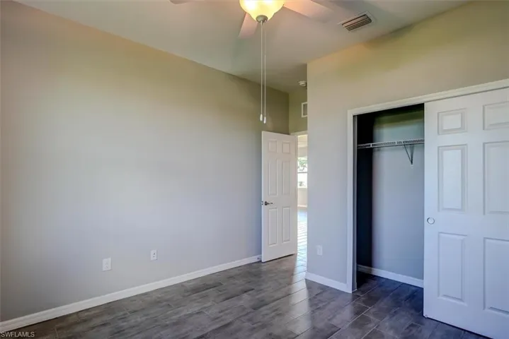 Unfurnished bedroom with dark wood-type flooring, ceiling fan, and a closet