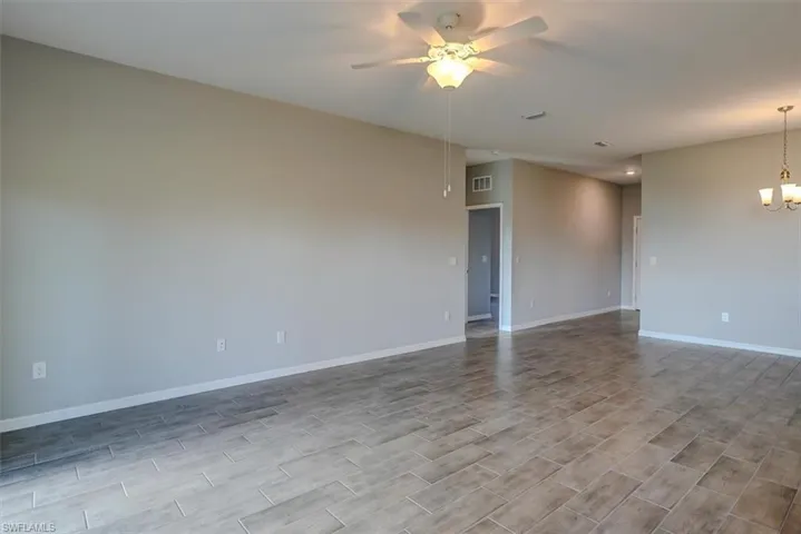 Spare room with ceiling fan with notable chandelier
