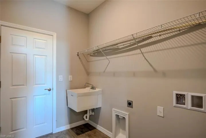 Clothes washing area with wood-look floors, hookup for an electric dryer, sink, and hookup for a washing machine