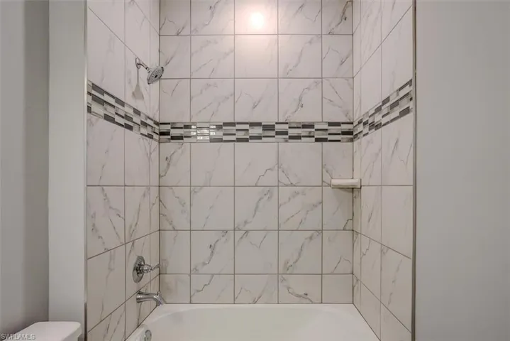 Bathroom featuring toilet and tiled shower / bath combo