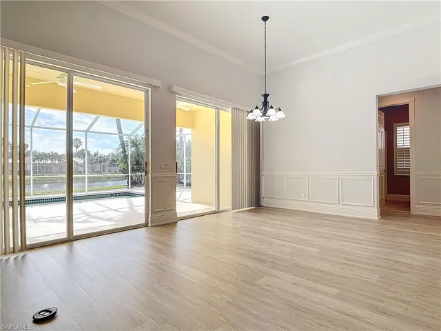 Empty room with a notable chandelier, crown molding, and light hardwood / wood-style floors