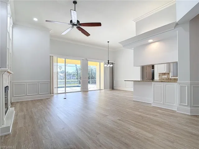 Unfurnished living room with crown molding, light wood-type flooring, and ceiling fan