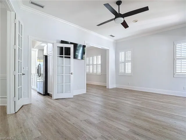 Empty room with ceiling fan, crown molding, and light wood-type flooring