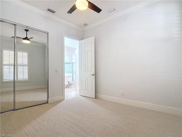 Unfurnished bedroom featuring crown molding, ceiling fan, light carpet, and a closet