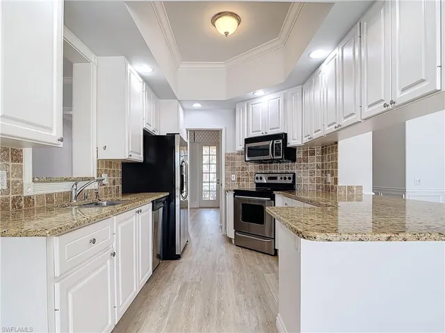 Kitchen featuring tasteful backsplash, stainless steel appliances, kitchen peninsula, and white cabinets