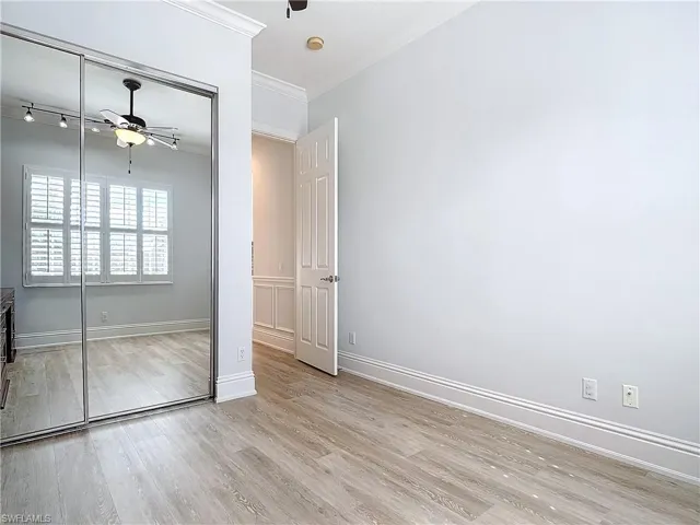 Unfurnished bedroom featuring crown molding, light hardwood / wood-style flooring, a closet, and ceiling fan