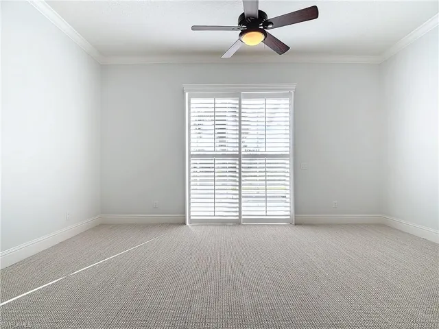 Carpeted empty room with ceiling fan and ornamental molding