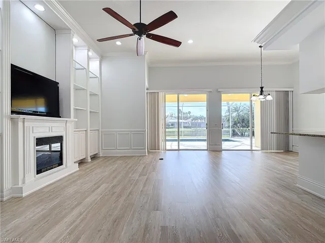 Unfurnished living room with ornamental molding, built in features, ceiling fan, and light hardwood / wood-style flooring