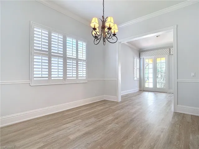 Empty room with ornamental molding, a chandelier, and light hardwood / wood-style floors