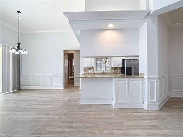 Kitchen with white cabinets, pendant lighting, stainless steel fridge, and an inviting chandelier