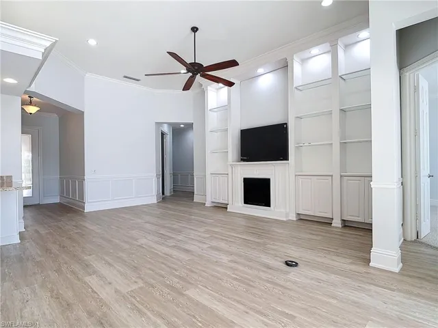 Unfurnished living room with crown molding, built in features, ceiling fan, and light hardwood / wood-style flooring