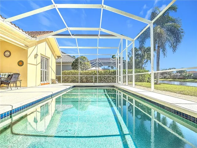 View of swimming pool with glass enclosure, a water view, and a patio