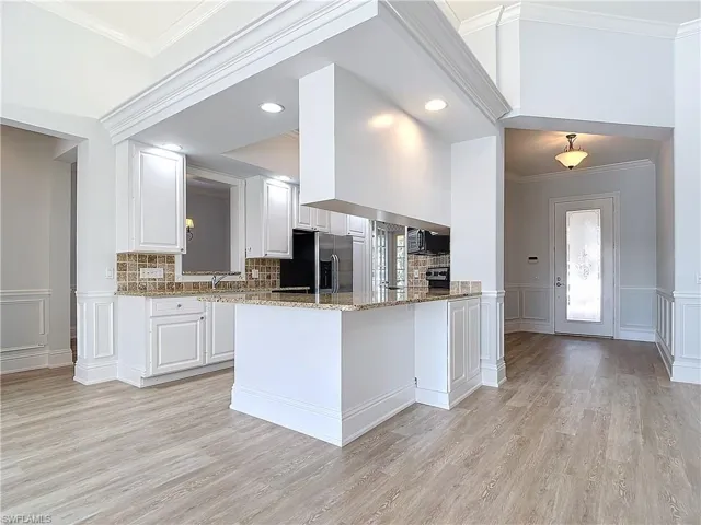 Kitchen featuring white cabinetry, light stone counters, stainless steel fridge with ice dispenser, kitchen peninsula, and light wood-type flooring