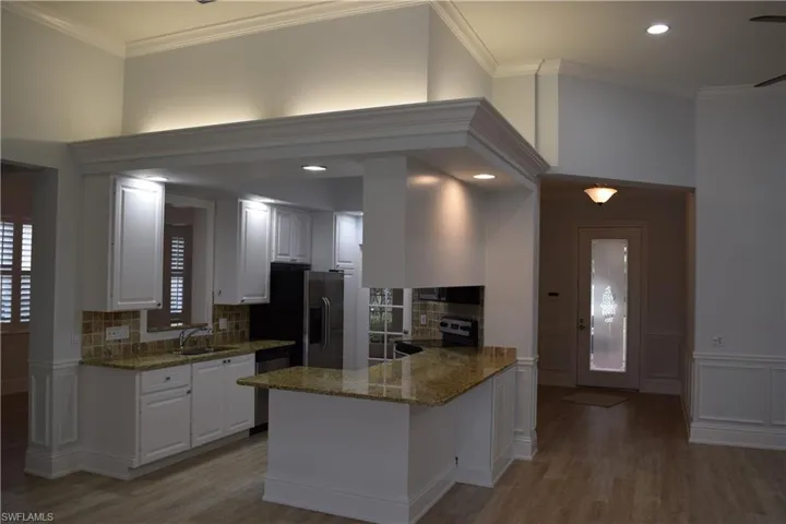 Kitchen featuring stainless steel appliances, white cabinets, sink, kitchen peninsula, and backsplash