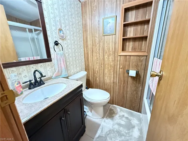 Full bath featuring a shower stall, vanity, light tile patterned floors, and built in features
