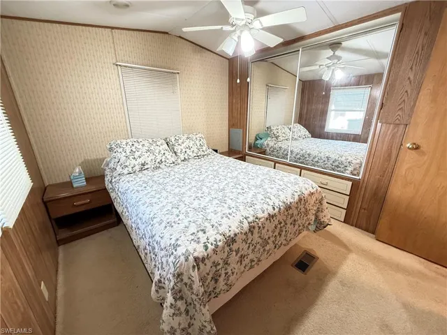 Carpeted bedroom featuring vaulted ceiling, ceiling fan, and wallpapered walls