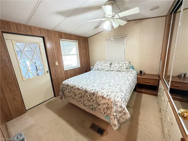 Bedroom with vaulted ceiling, a closet, light carpet, ceiling fan, and a textured ceiling