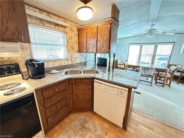 Kitchen with electric range oven, dishwasher, light wood finished floors, brown cabinetry, and plenty of natural light
