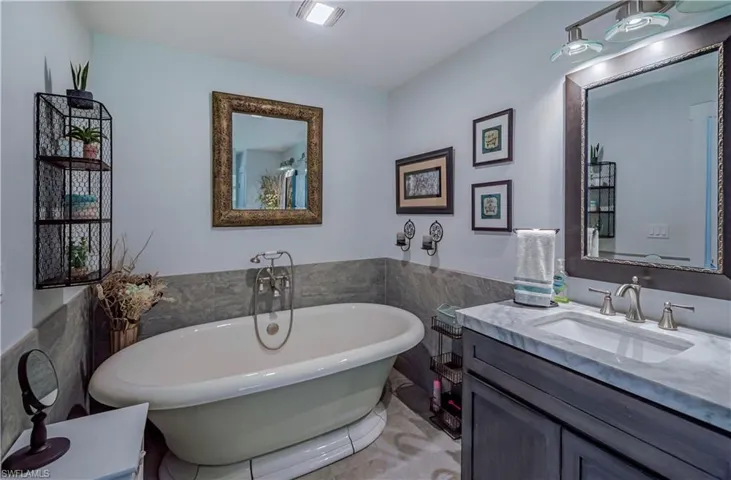 Full bath featuring a freestanding tub, tile walls, vanity, and a wainscoted wall