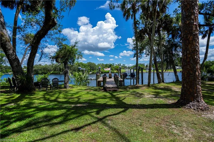 View of green lawn with a boat dock and a water view